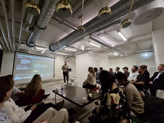 Mo presenting a slide titled "The hidden cost of slow consultant onboarding" to a seated audience.