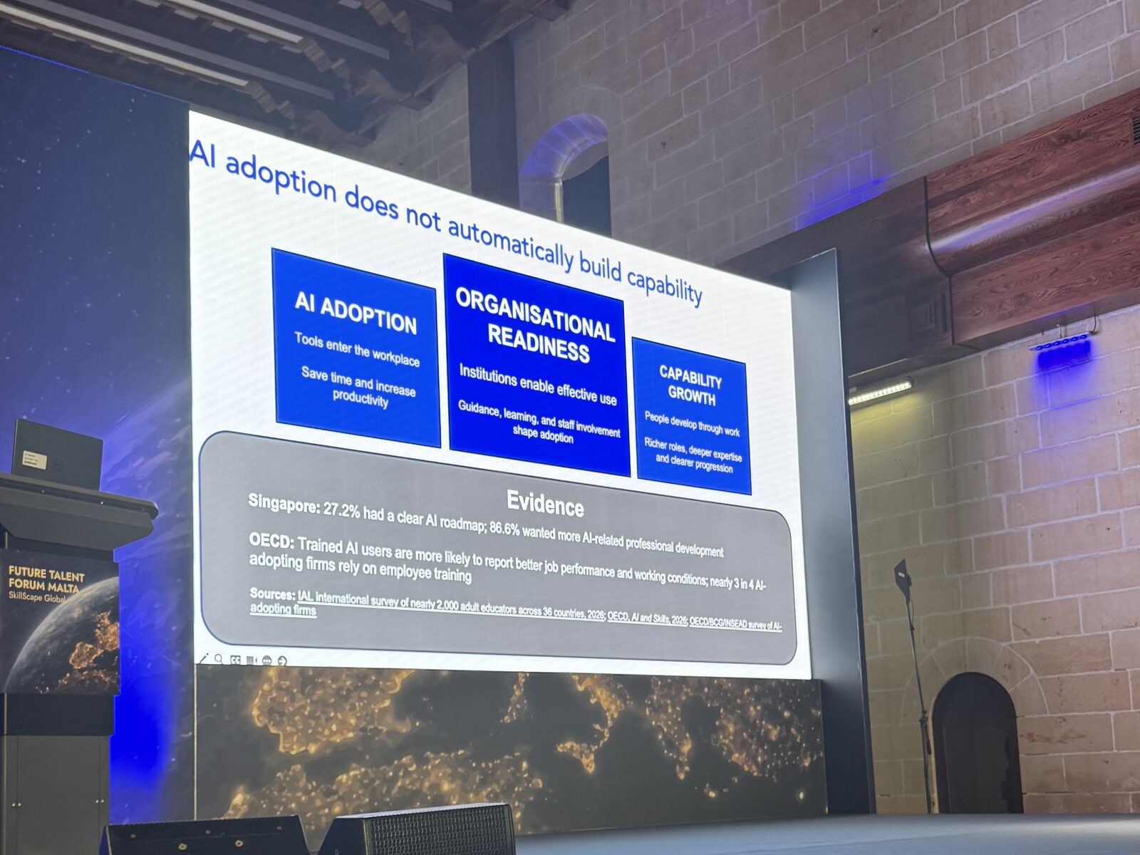 A slide from El Iza Mohamedou's keynote reading AI adoption does not automatically build capability, showing AI adoption, organisational readiness and capability growth